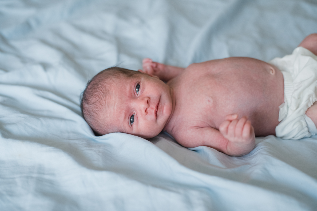 baby lying on bed-pensacola newborn photographer