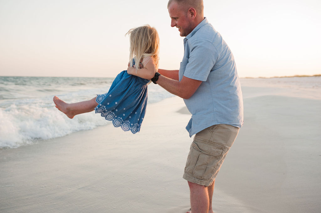 dad swinging daughter in waves- Navarre Beach Family Photographer