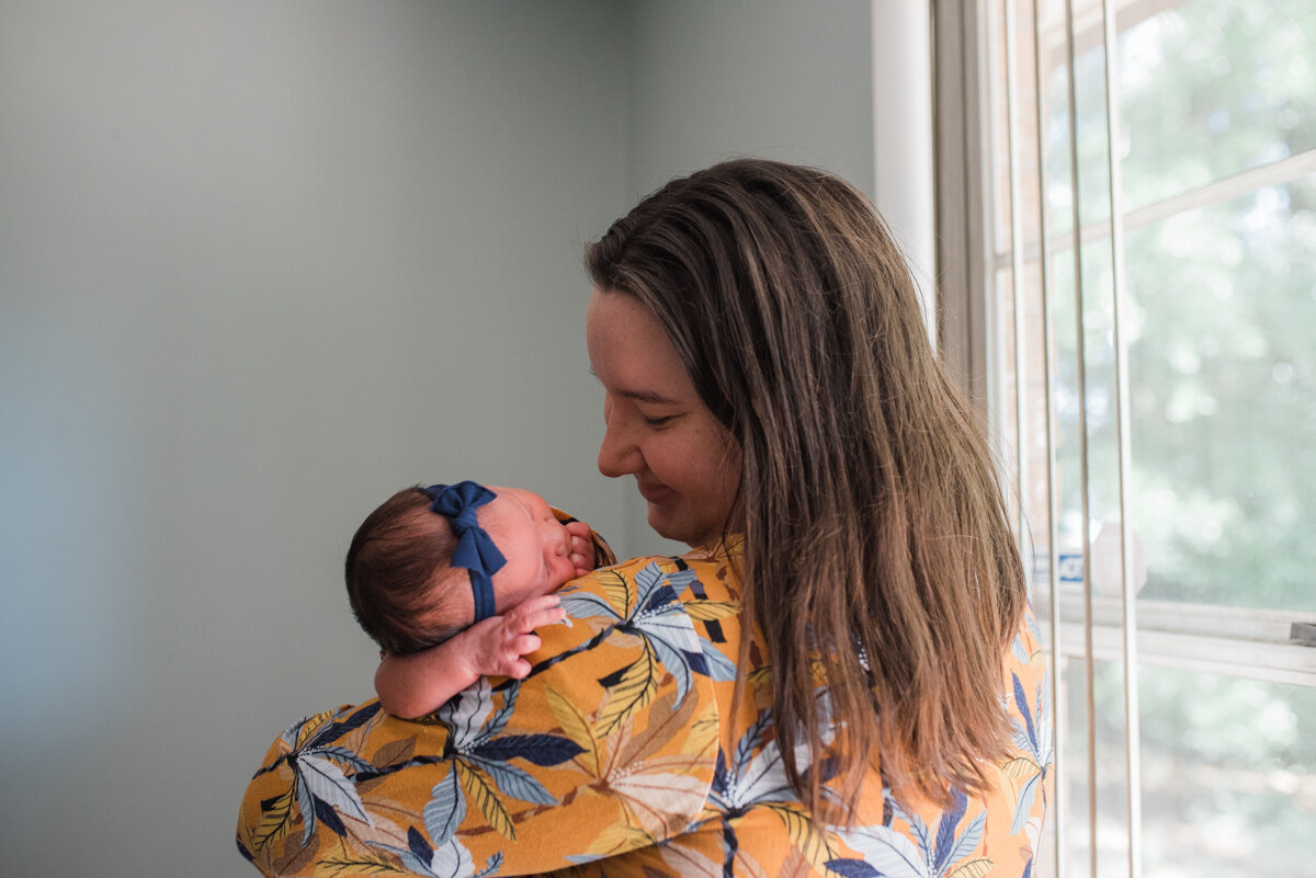 mom with newborn by wall-pensacola newborn photographer