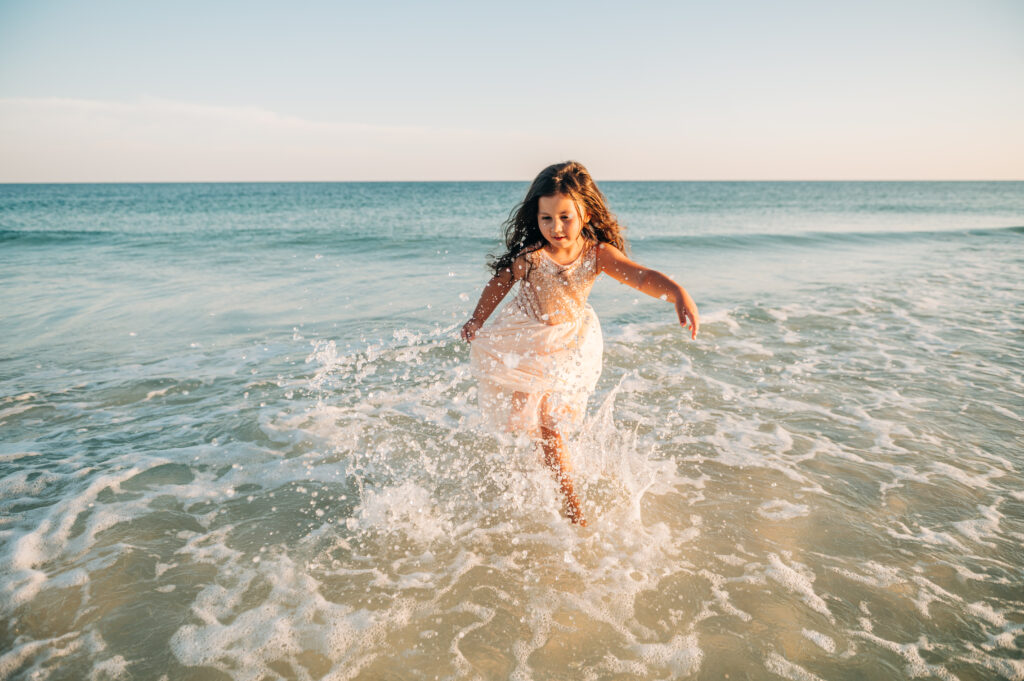 girl running thru water at pensacola beach